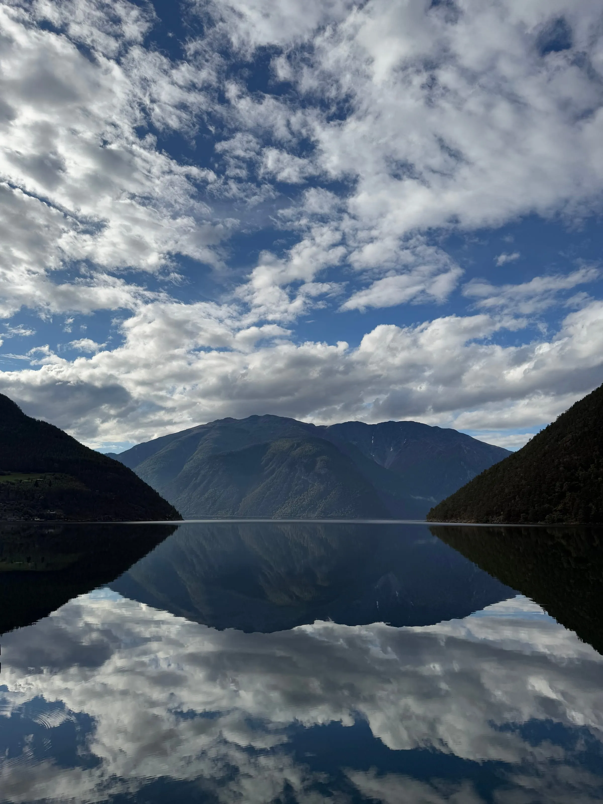 Sognefjorden i blikkstille vær, med fjellsidene speilet i vannet.